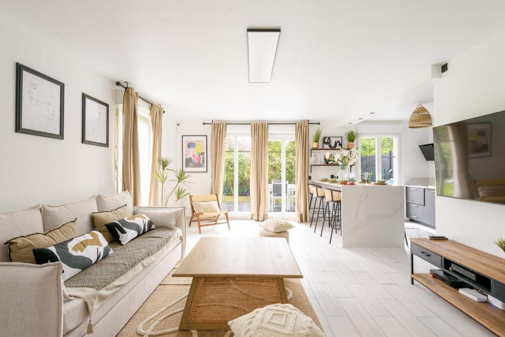 ein Wohnzimmer mit Sofa und Tisch in der Unterkunft La Villa Nova Pomponne - 3 chambres et jardin in Magny-le-Hongre