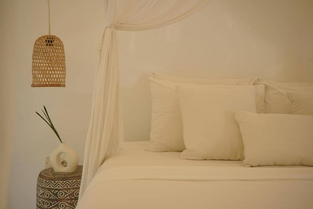 un letto bianco con cuscini bianchi in una camera da letto di Joy Canggu a Canggu