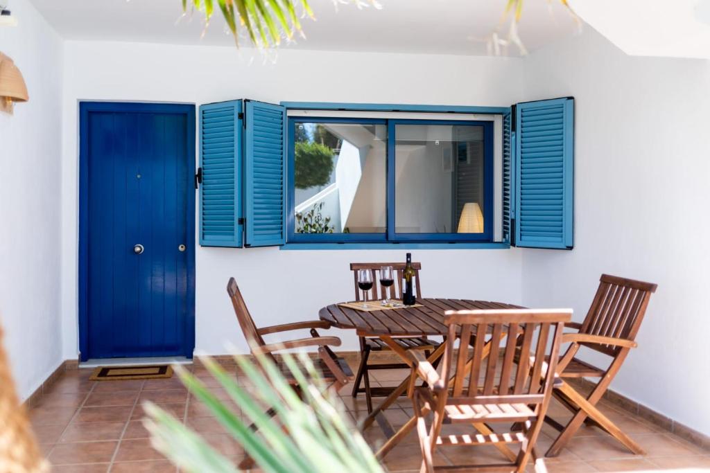 a dining room with blue shutters and a table and chairs at Casa Ardisia, con terraza y aparcamiento in Las Negras