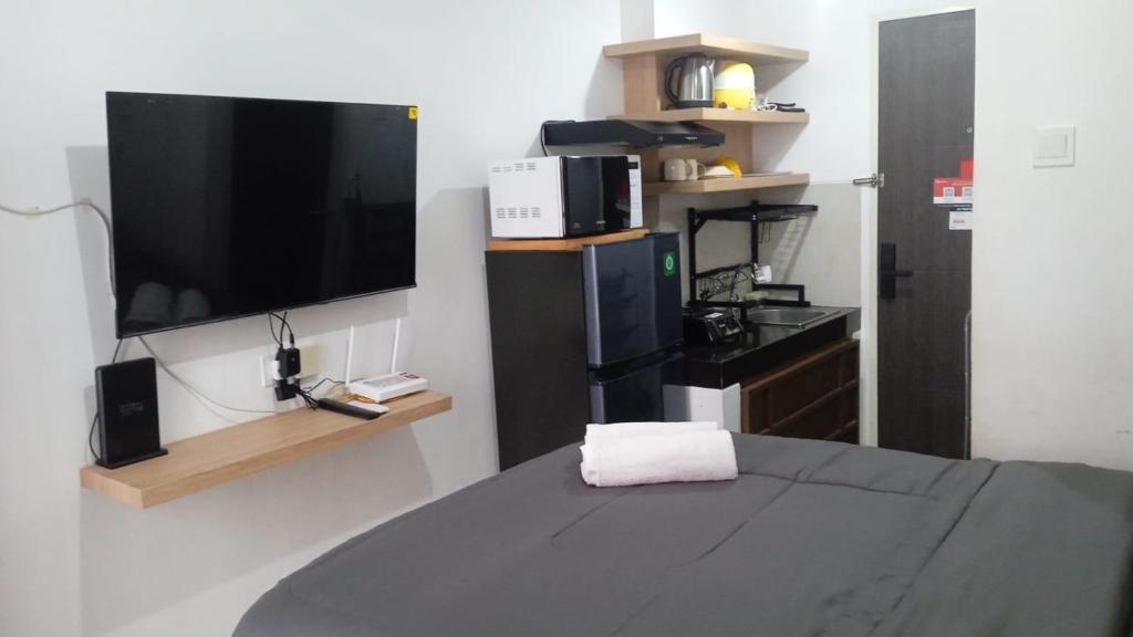 a room with a bed with a tv at FREE WIFI, NETFLIX, SMART TV, MINERAL WATER, AMENITIES - Studio with Foldable Wall Bed at Serpong Garden Apt in Cisauk 1
