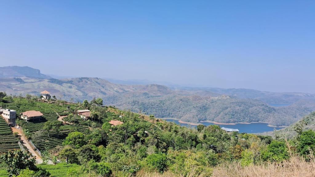 a village on a hill with a river and mountains at Heritage Farm Kerala in Idukki