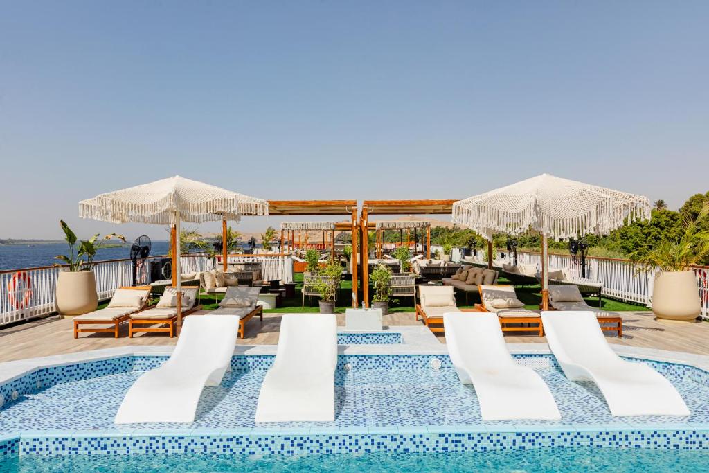 a pool on the roof of a hotel with chairs and umbrellas at Tamr Nile Cruise - 04 Nights Every Monday from Luxor - 03 Nights Every Friday from Aswan in Luxor