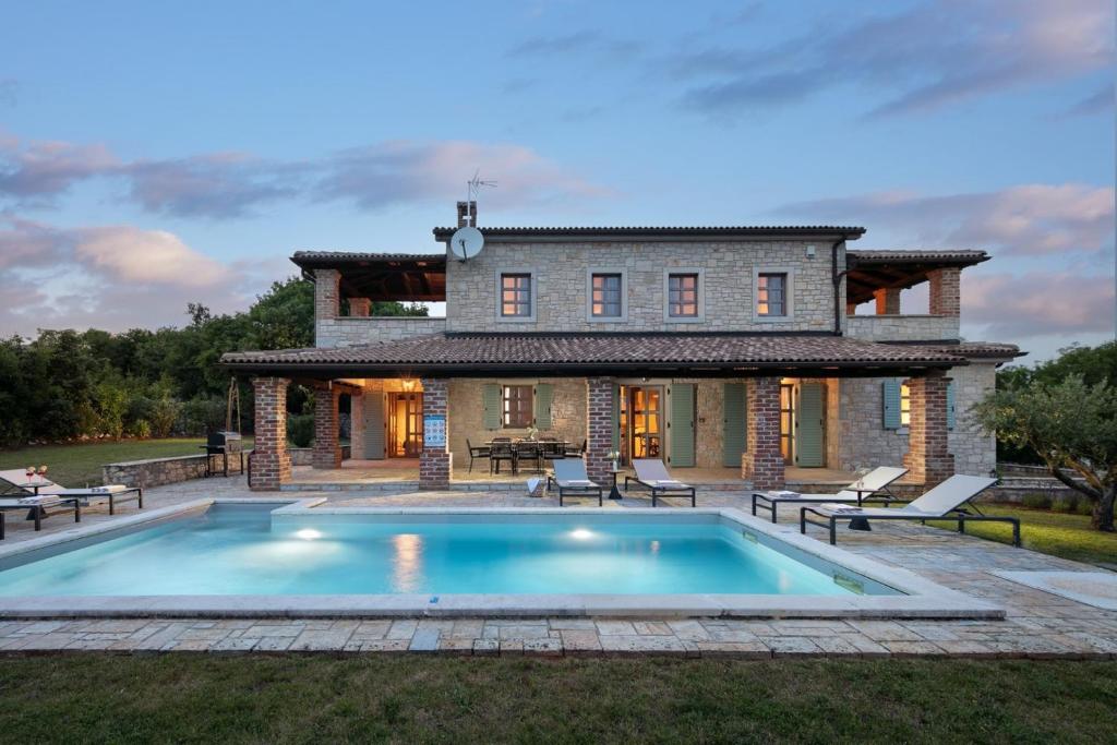 Rustic Villa Calluna & Cardamine with a pool في Sveti Lovreč Pazenatički: منزل به حوض سباحة أمام المنزل