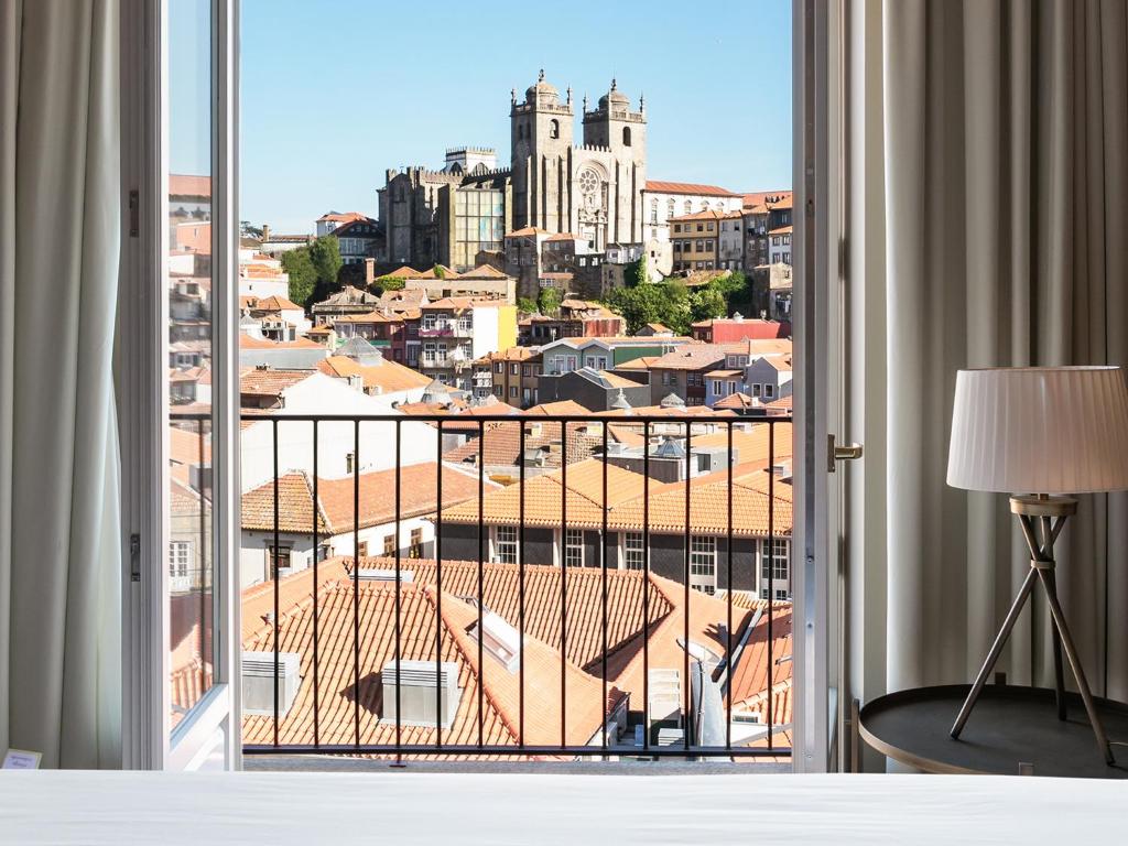 a bedroom with a view of a city from a window at Casa da Companhia, Vignette Collection by IHG in Porto
