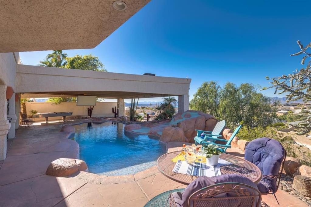 une maison avec une piscine et une table avec un ordinateur portable dans l'établissement Peruvian-4 Bed Desert Oasis -Pool, Hot-Tub &Outdoor Kitchen, à Lake Havasu City