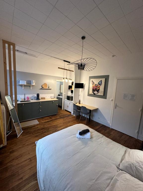 une chambre avec un grand lit blanc et un bureau dans l'établissement Émeraude 1, à Vichy