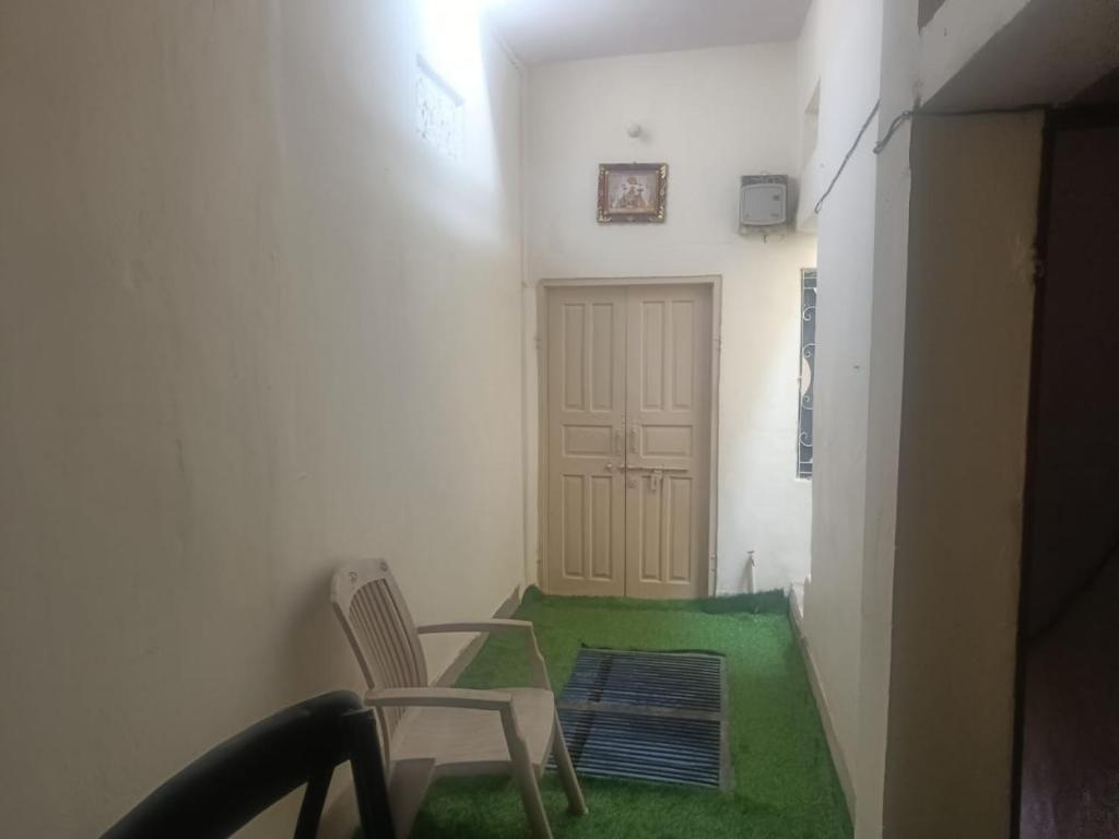 a room with a chair and a door with a green floor at Rudra The Stay in Jaipur