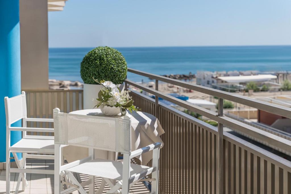 a table and chairs on a balcony with the beach at Hotel Lina in Misano Adriatico