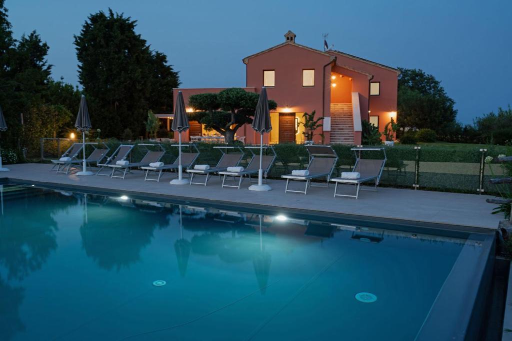 a group of chairs sitting next to a swimming pool at Relais Tenuta Santori in Cossignano