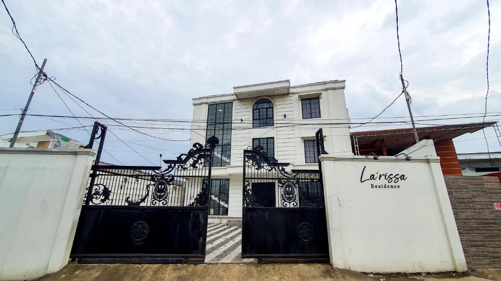 a white house with a black gate in front of it at La'Rissa Residence by ARBA in Karawang
