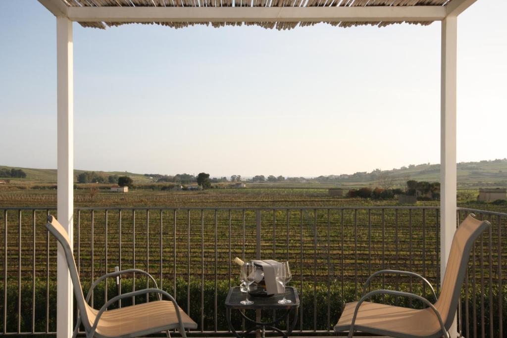 a table and chairs on a porch with a view of a field at Il Vigneto Resort in Menfi