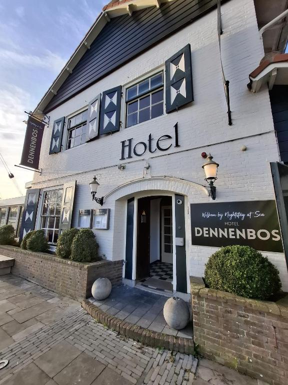 a hotel building with a sign in front of it at Strandhotel Dennenbos in Oostkapelle