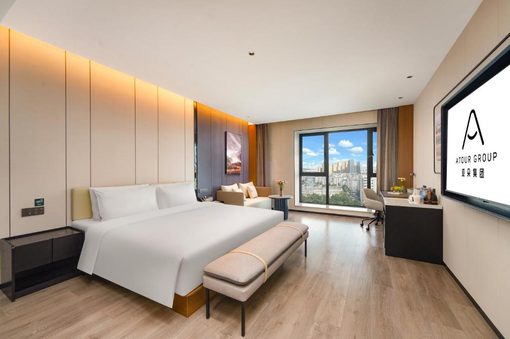 a hotel room with a large bed and a tv at Atour Hotel Kunming Changshui International Airport Cloud Cube in Kunming