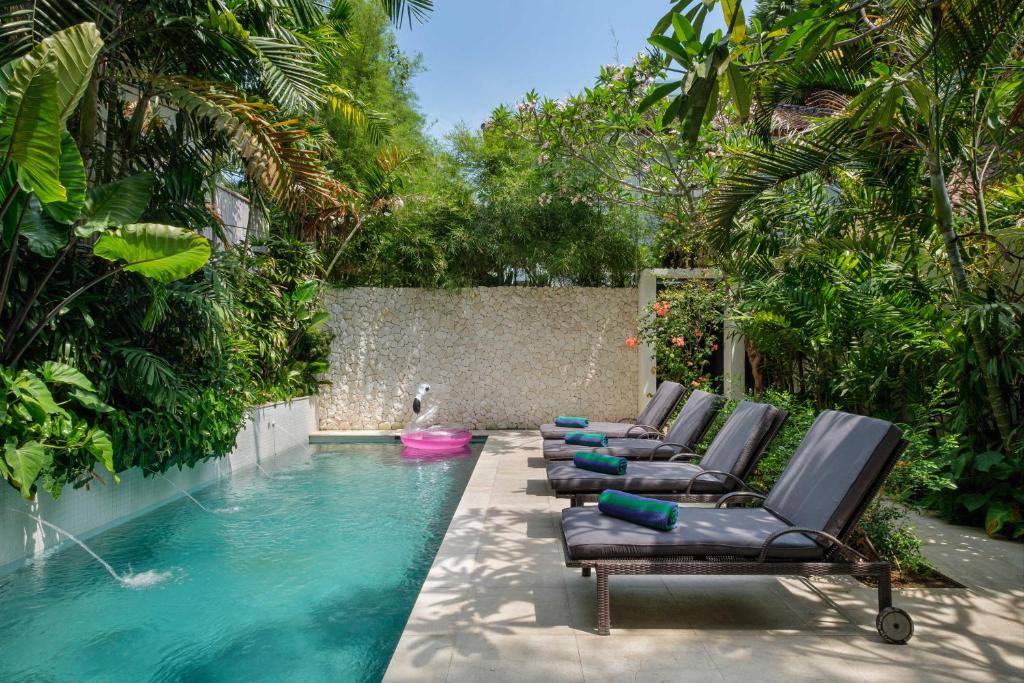 a row of chaise lounge chairs next to a swimming pool at Villa Levi by GORO in Seminyak