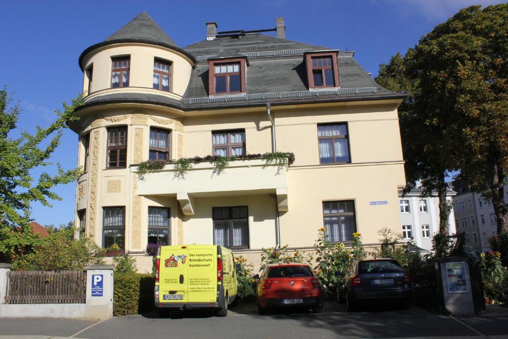 une grande maison avec des voitures garées devant elle dans l'établissement Pension Vogtländer, à Plauen