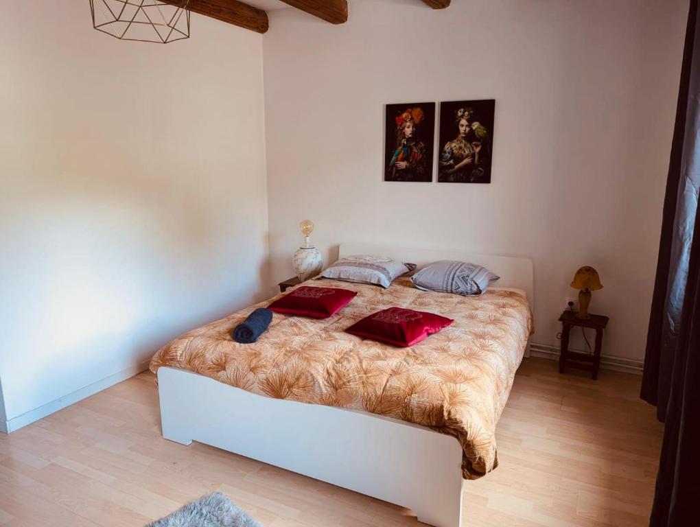 a bedroom with a large bed with red pillows on it at La Mariefacture comme un charme in Haute-Vigneulles