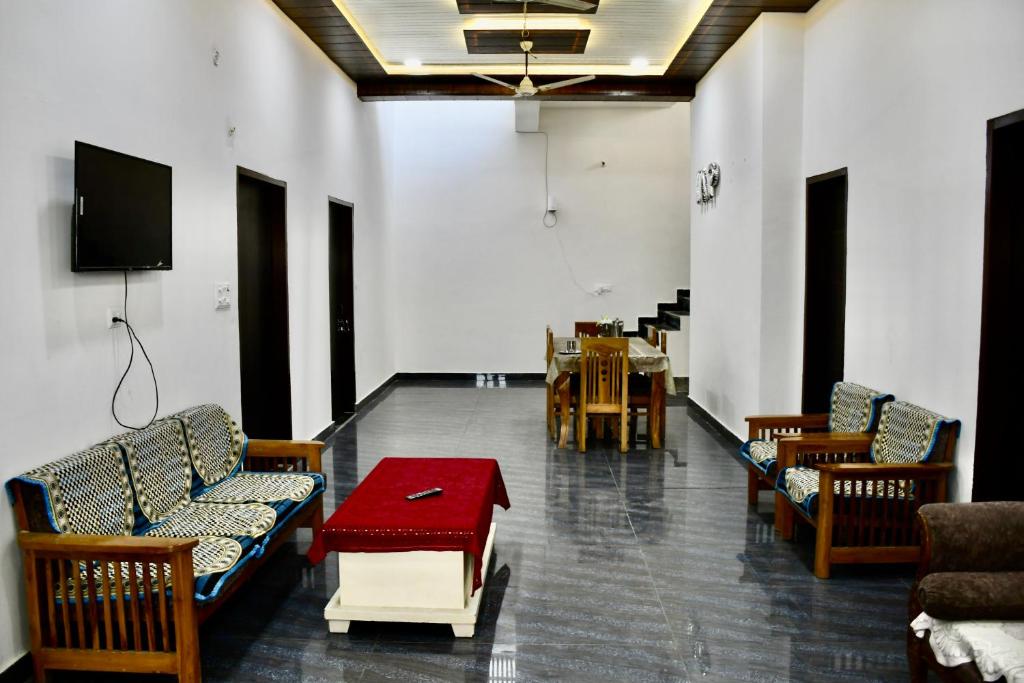 a waiting room with chairs and a table and a tv at Village Villa Agra in Tājganj