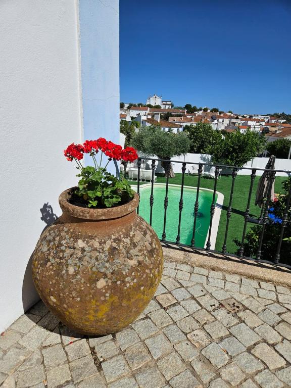 a large vase with red flowers sitting next to a building at Solar de Arrayollos by PURUS in Arraiolos