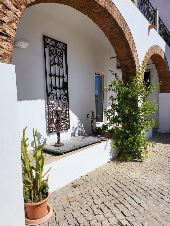a courtyard of a house with an archway and plants at Solar de Arrayollos by PURUS in Arraiolos