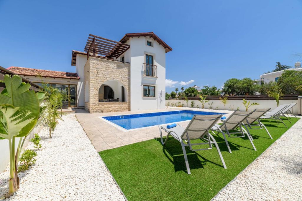 a villa with a swimming pool and chairs in a yard at Kymma Villa #12 in Ayia Napa