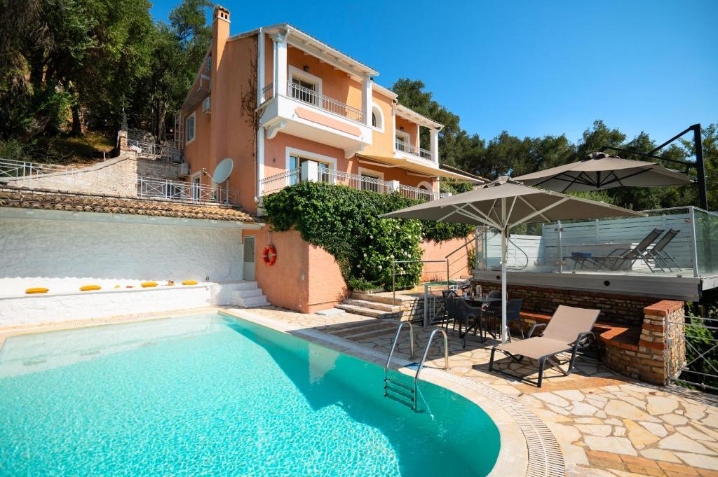 a house with a swimming pool and an umbrella at Villa Anastasia in Corfu