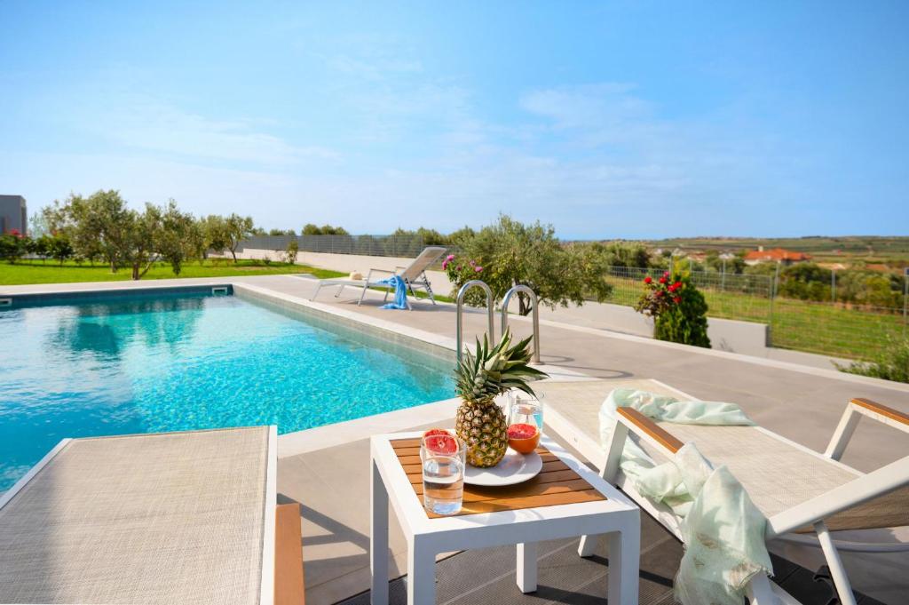 a patio with a table and chairs next to a swimming pool at Sunset Villa in Paralia Dionysiou