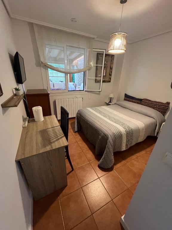 a bedroom with a bed and a desk and a television at Habitación con baño privado y jardín Cerca de las playas in Boó de Piélagos