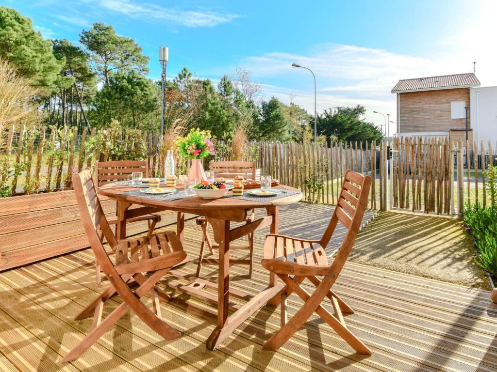ein Holztisch und Stühle auf einer Holzterrasse in der Unterkunft Apartment Soleil couchant by Interhome in Mimizan