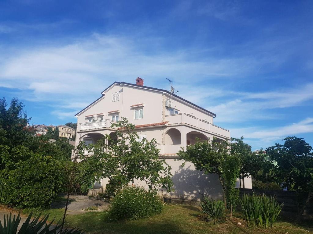 a large white house with trees in front of it at Apartment Mari in Lopar