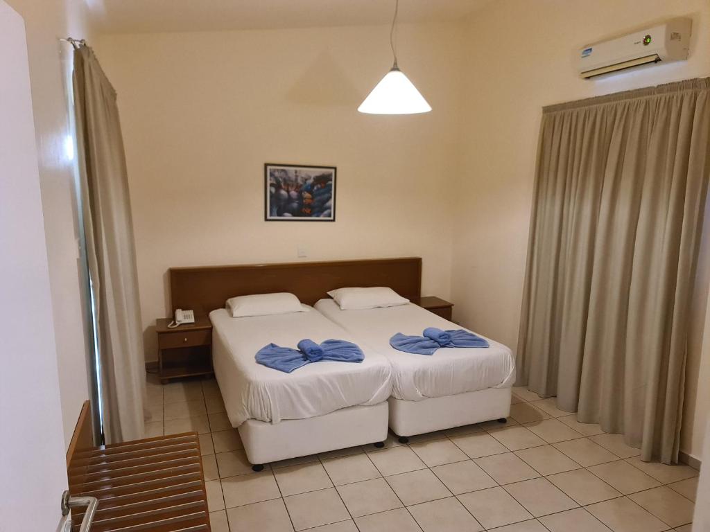 a bedroom with two beds with blue towels on them at Nissiana Hotel & Bungalows in Ayia Napa