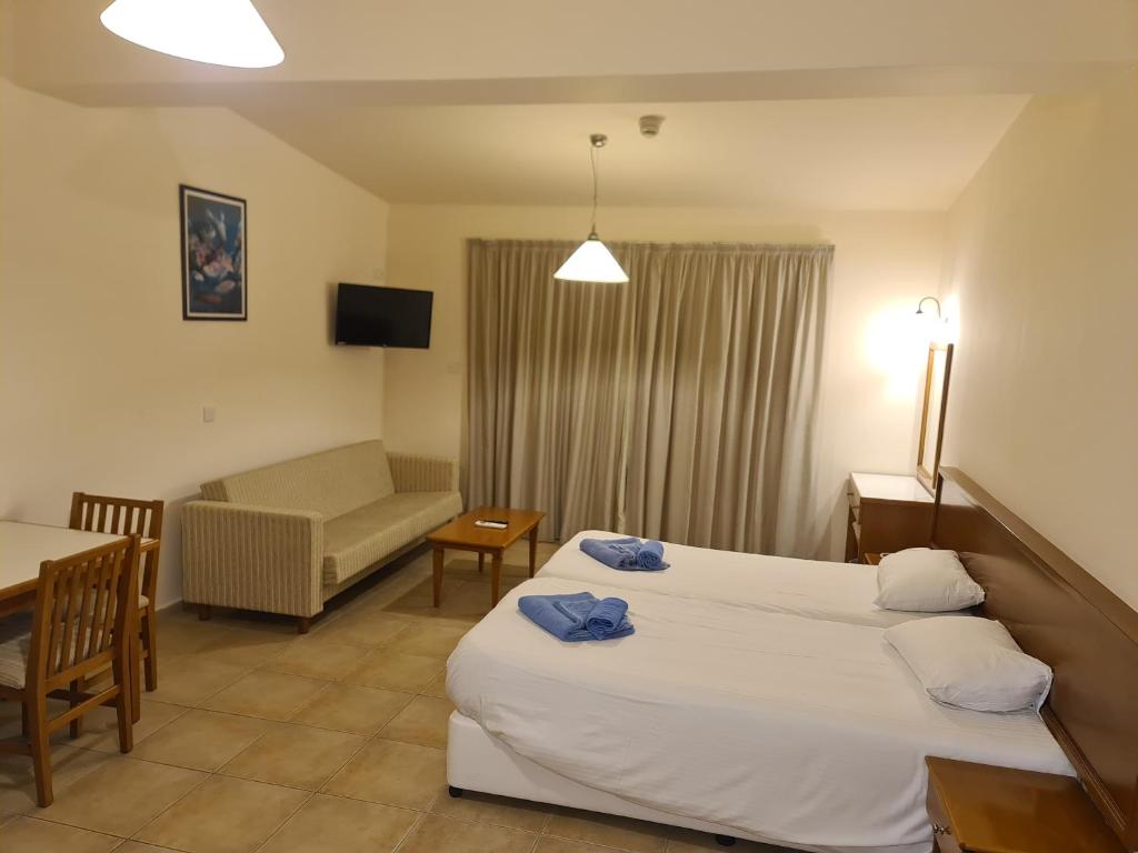 a hotel room with two beds and a couch at Nissiana Hotel & Bungalows in Ayia Napa