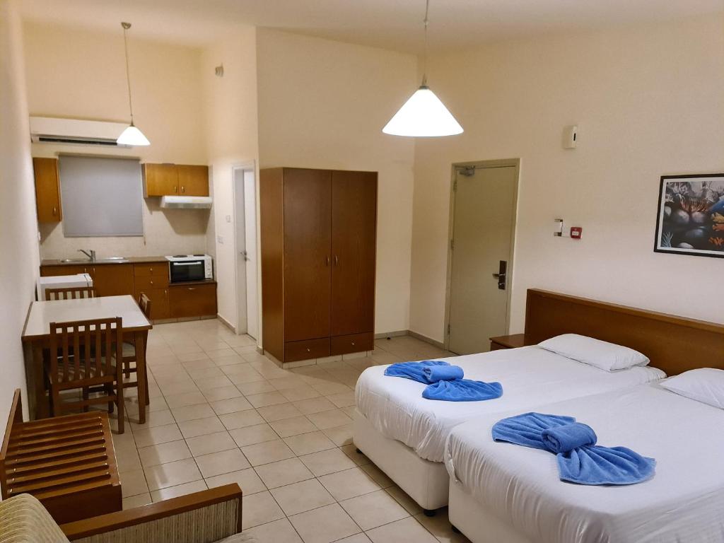 a hotel room with two beds and a kitchen at Nissiana Hotel & Bungalows in Ayia Napa