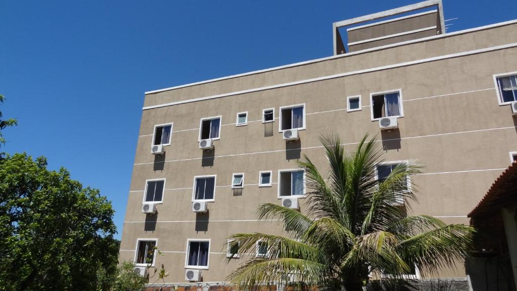 un edificio con ventanas y una palmera frente a él en Hotel Solar De Itaborai, en Itaboraí