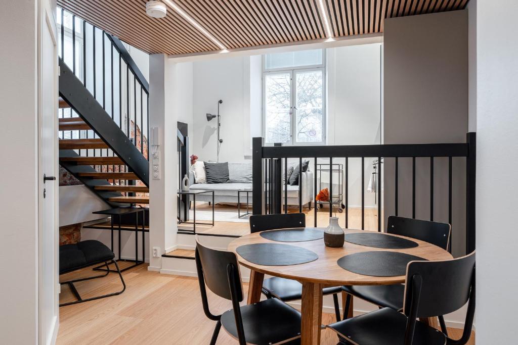 a dining room and living room with a table and chairs at Stylish Loft next to City Center & Lake Pyhäjärvi in Tampere