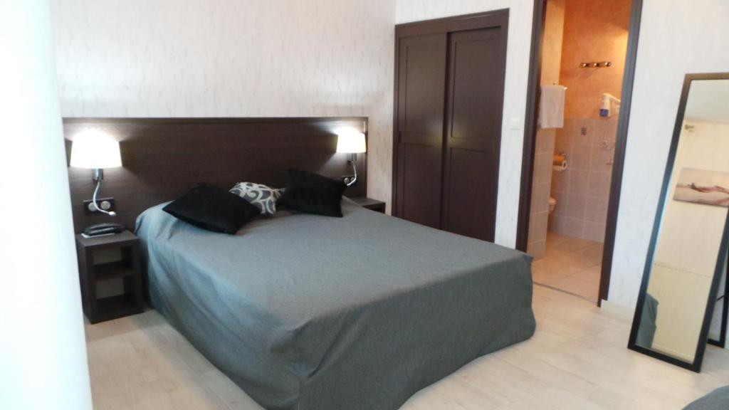 ein Schlafzimmer mit einem großen Bett mit zwei Kissen darauf in der Unterkunft Hotel La Renaissance in Cherbourg en Cotentin