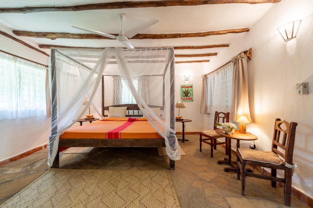 una camera con letto e zanzariera di Diani Marine Divers Village a Diani Beach