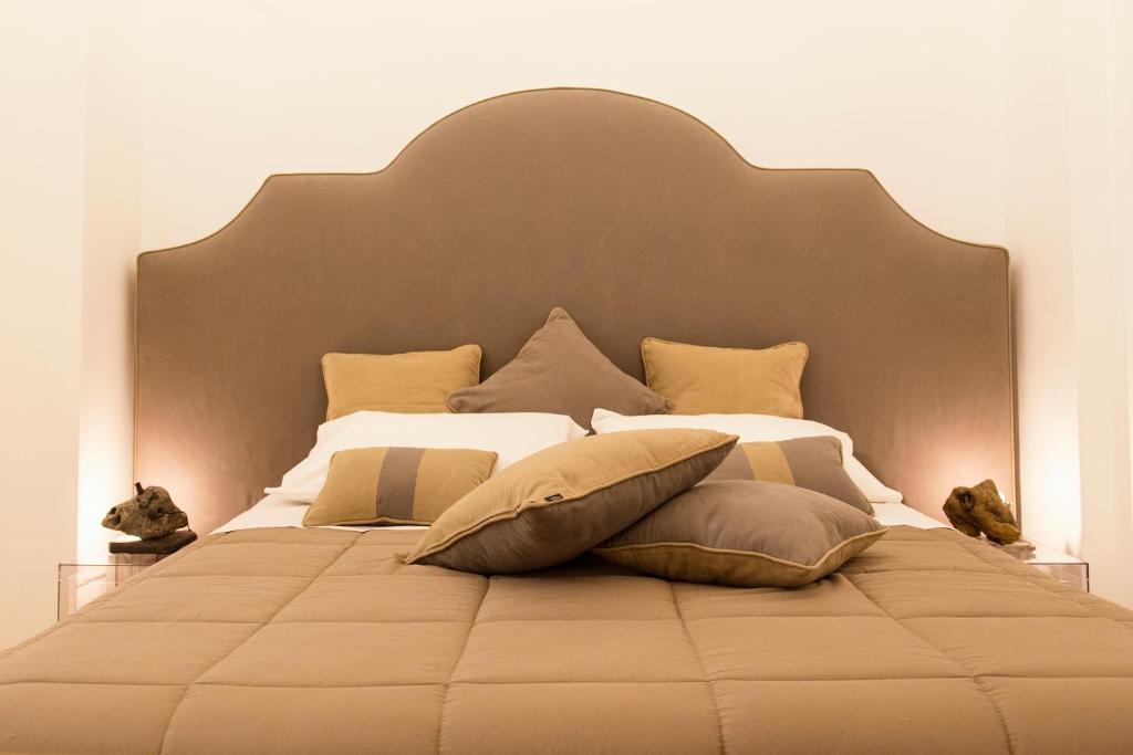 uma cama grande com uma grande cabeceira e almofadas em Dammuso Suite Noto em Noto