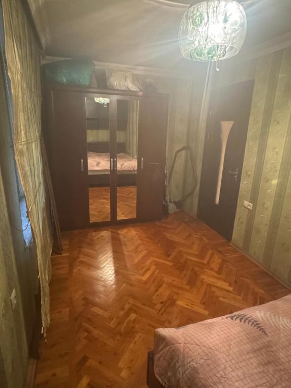 ein Schlafzimmer mit Holzboden und ein Zimmer mit einem Bett in der Unterkunft Home in Baku