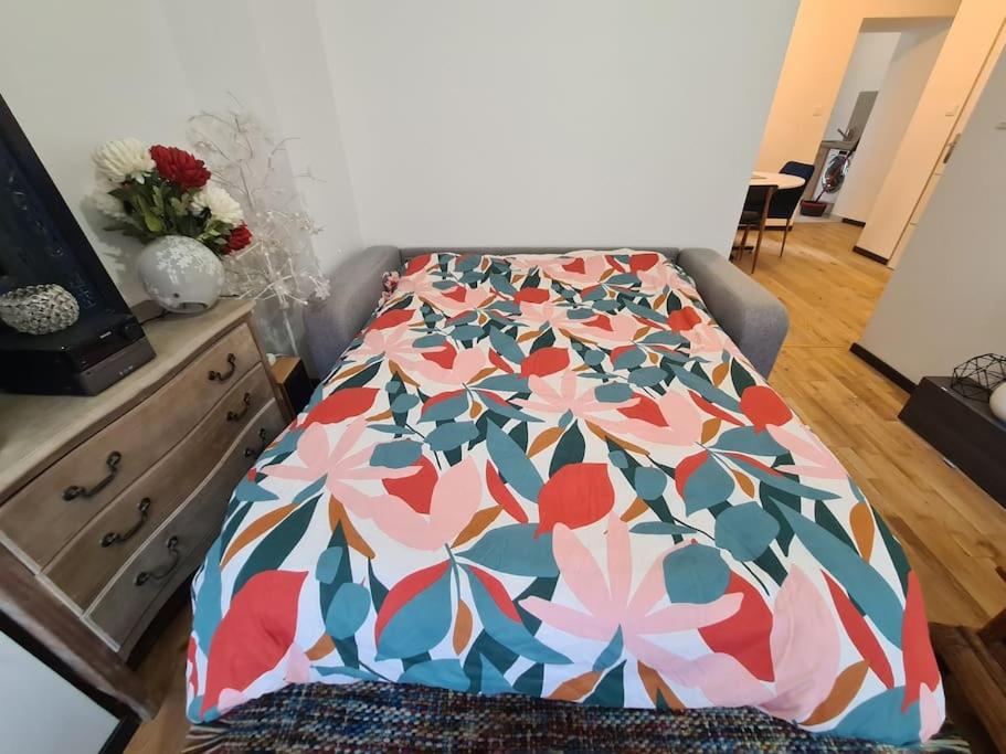 een bed met een gebloemd dekbed in een kamer bij La cigogne d'Alsace 2 in Sélestat