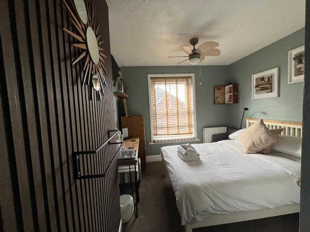 a bedroom with a bed and a clock on the wall at Kelston Guest House in Weymouth