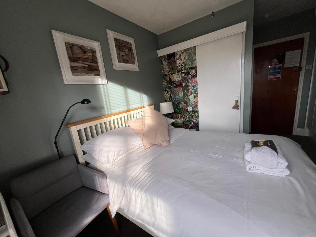 a bedroom with a white bed with a cat on it at Kelston Guest House in Weymouth