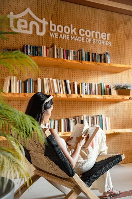 a woman sitting in a chair reading a book at tent Bahia de Palma in El Arenal