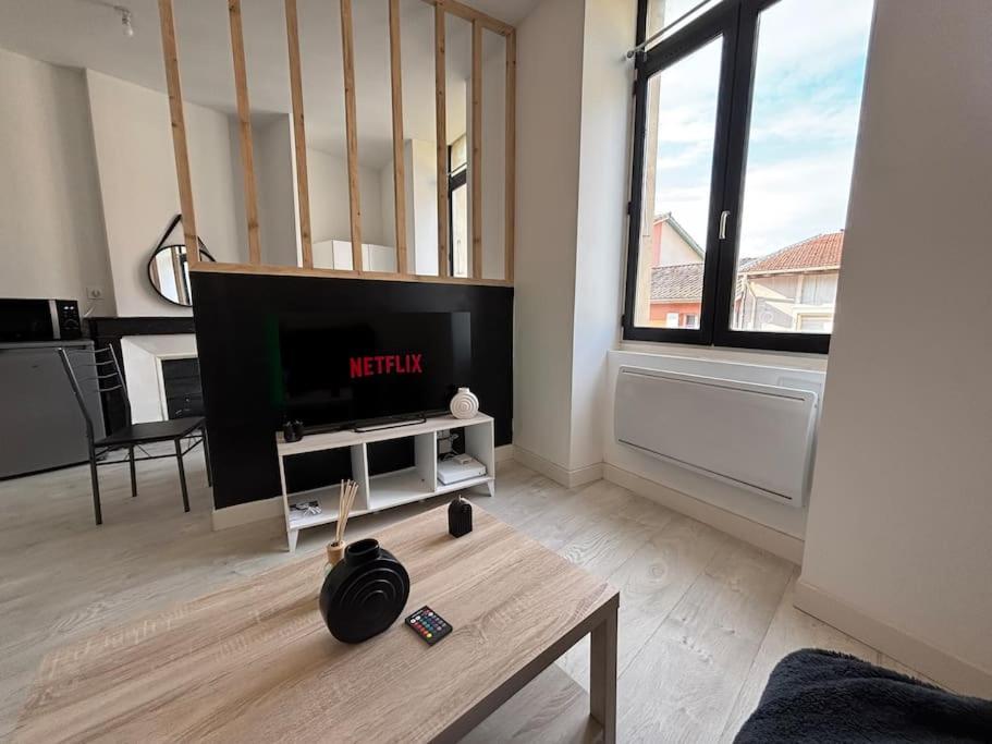 a living room with a flat screen tv and a table at Appartement rénové, proche gare in Bourg-de-Péage