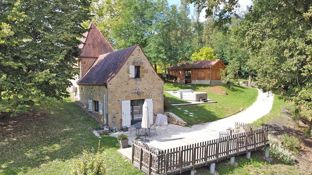 une petite maison avec une clôture dans la cour dans l'établissement Maison climatisée avec jacuzzi à 10 min de Sarlat, à Sarlat-la-Canéda