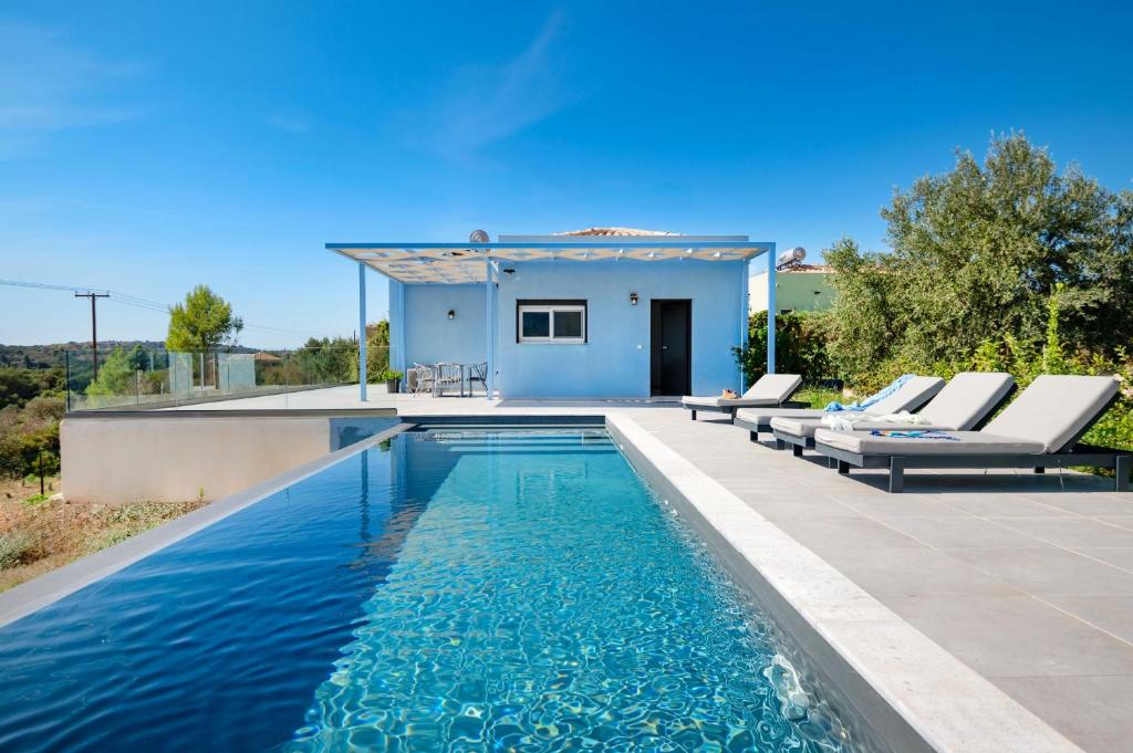 una piscina con sedie e una casa di Villa Antreas Mentoros a Karavádhos