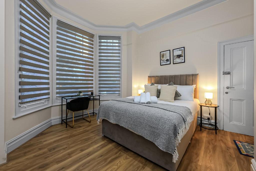 a bedroom with a large bed and windows with shutters at Cozy Sunlit Studio with Kitchenette in London