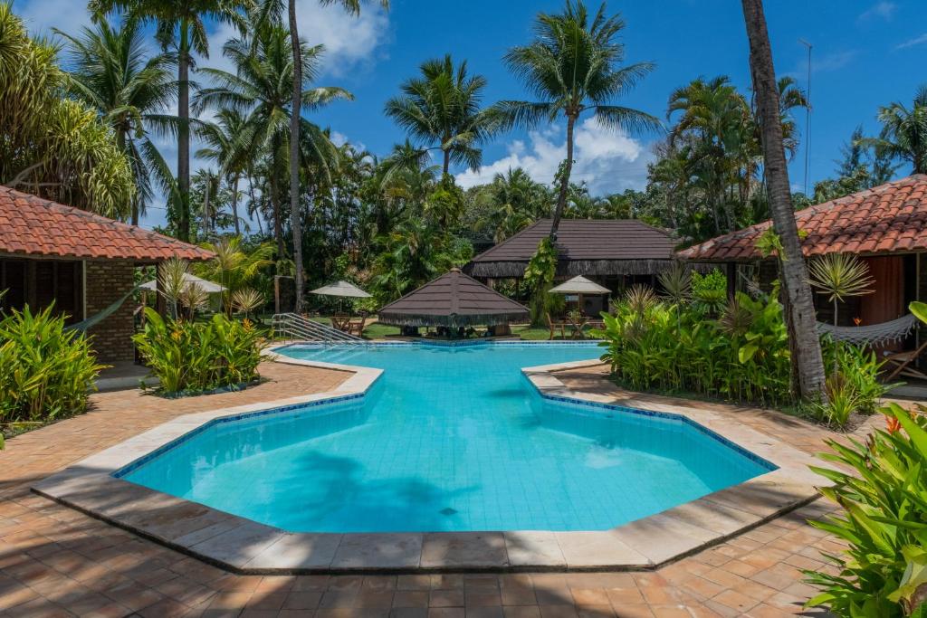 a swimming pool in front of a resort with palm trees at Pousada Berro do Jeguy in Pipa