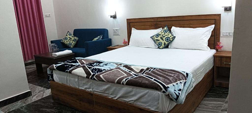 a bedroom with a bed and two blue chairs at Rainbow Homestay Khajuraho in Khajurāho