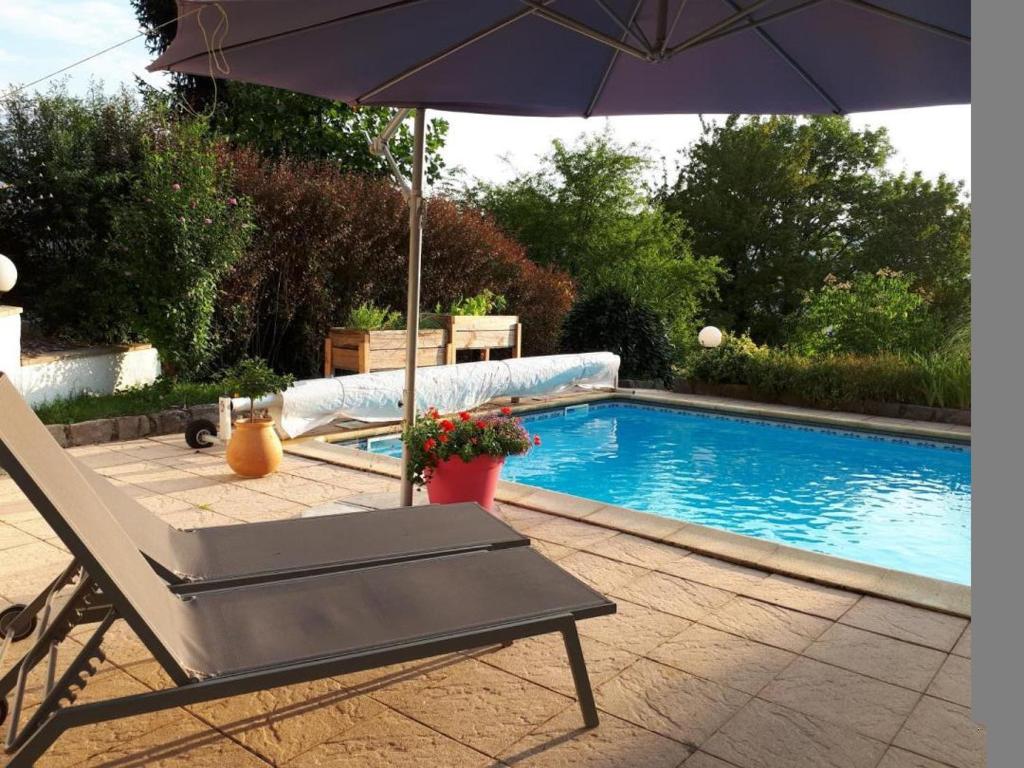 an umbrella and a chair next to a swimming pool at L'ermitage in Chambéry