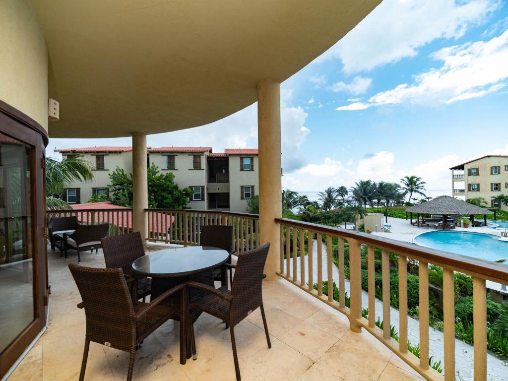 a balcony with a table and chairs and a pool at Residences at Barrier Reef 8B Oceanview 2 BR by Stay Floreo in San Pedro